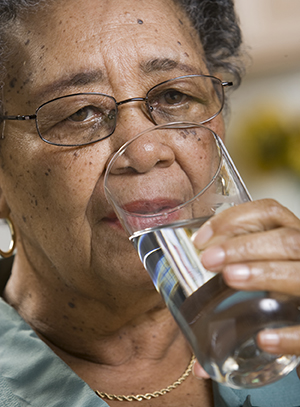 Mujer que bebe un vaso de agua.