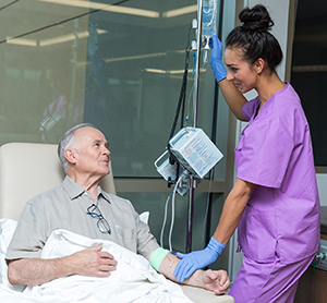 Proveedor de atención médica atendiendo a un hombre que recibe terapia de infusión.